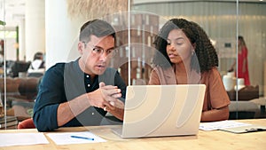 Two busy business man and woman working on computer discussing project at work.