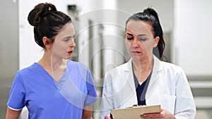 Two busy female doctors having a conversation on the corridor