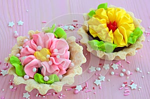 Two cakes in a basket with butter cream on a pink table.