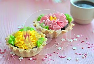 Two cakes with cream and a cup of coffee are on a pink table.