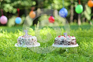 Two cakes with a lit candles in the shape of