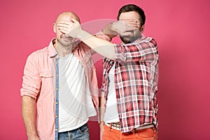 Two calm Caucasian men in casual clothes closed their eyes to each other with their hands.