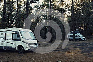 Two camper van parked in the wild with forest woods and trees all around. Concept of alternative vanlife lifestyle and transport