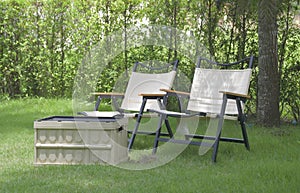 Two camping chairs sit next to a utility box on the outdoor lawn