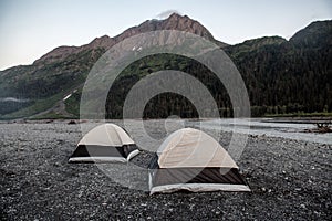 Two camping tents in mountain valley near the river in Alaska, USA.