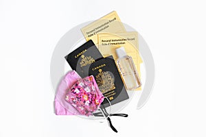 Two Canadian passports with yellow immunity vaccination records, face cotton protective masks and sanitizer. Safety measures