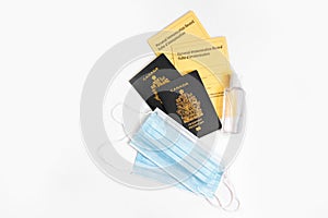 Two Canadian passports with yellow immunity vaccination records, face sanitary blue masks and sanitizer. Safety measures against