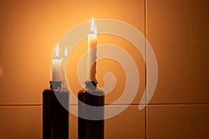 Two candles in the ceramic bottles next to the wall