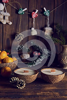Two candles in a coconut shell on the background of the Christmas decor.