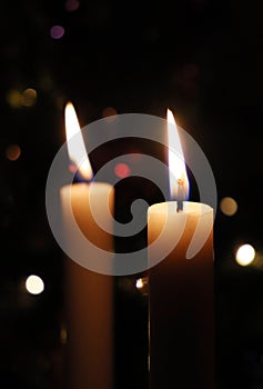 Two candles in front of a Christmas tree