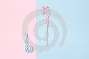 Two candy canes on pastel blue and pink background. Minimal composition with copy space. Holiday concept