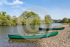 Two canoes lie on the bank of the river