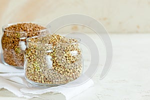 Two cans of buckwheat on white table with copy space.