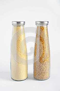 Two cans filled with bulgur and couscous on a white isolated background