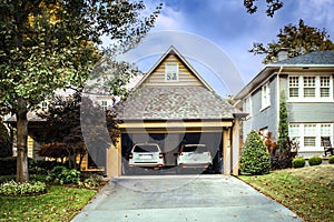 Two car garage open with two white SUVS parked inside on autumn day