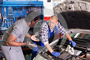 Two car mechanic diagnosing auto engine problem in service
