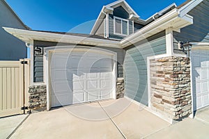 Two car residential garage with dormer gray wall siding and white panelled doors