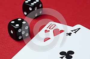 Two cards and black dice on a red background, close-up