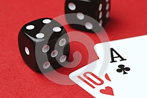 Two cards and black dice on a red background, close-up