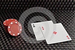 Two cards and red poker chips on a black background