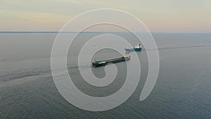 Two cargo ships a cargo ship and a tanker sail towards each other in the bay, aerial top view