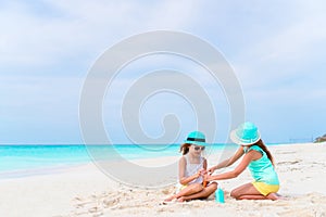 Two caring girls take care of each other on white beach. The concept of protection from ultraviolet radiation