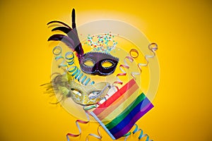 Two carnival masks with confetti and gay pride flag