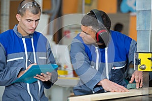 Two carpenters cutting wood in workshop