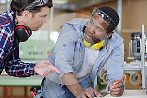 two carpenters with electric drill drilling wood plank at workshop