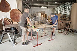 Two carpenters making furniture in a workshop