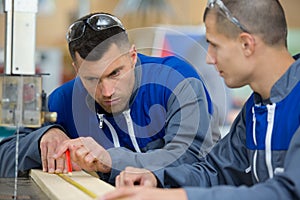 two carpenters talking while holding papers and ruler