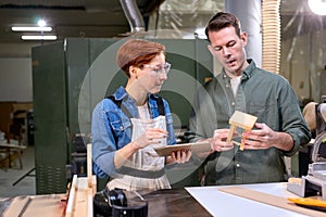 Two carpenters working with equipment on wooden table in carpentry shop, make stool