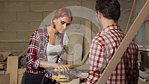 Two carpenters working on wood plank at the workshop