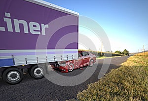 Two cars accident. A red sedan crashed against the back of a big truck