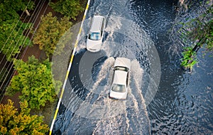 Two cars are moving on a flooded street after heavy rain