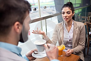 Two casual business travellers having a conversation at an airport cafÃ©