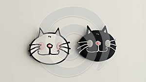 Two cats magnets on a fridge.
