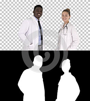 Two caucasian and afro american smiling doctors standing looking