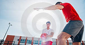 Two caucasian basketball player fighting for ball possession at the basketball court on a sunny day