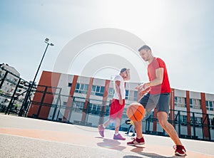 Two caucasian basketball player fighting for ball possession at the basketball court on a sunny day