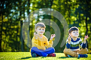 Two Caucasian boy brother friends sitting down on fresh green gr