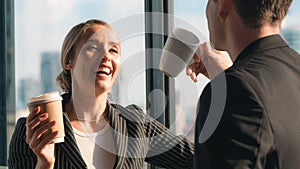 Two caucasian business people look happy while having business talk and drinking coffee in office