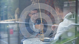 Two Caucasian businessmen sitting in cafe and talking. Confident young male entrepreneurs discussing business in canteen