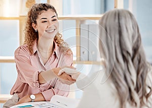 Two caucasian businesswomen shaking hands in a meeting at work. Business professionals greeting and making deals with