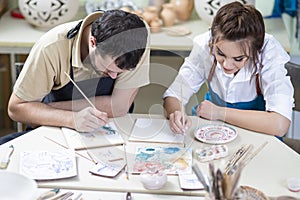 Two Caucasian Ceramists Painting and Glazing Clay Crafts Together