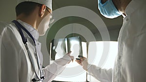 Two caucasian doctors view mri picture and discussing about it. Male medics consult with each other while looking at x