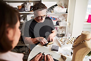 Two Caucasian jewelers working together in their workshop