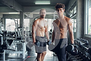 Two Caucasian muscular men with dumbbell