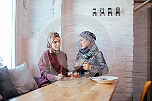 Two caucasian muslim woman drinking tea in cafe