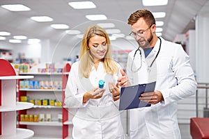 Two caucasian pharmacists are discussing medication, using a digital tablet